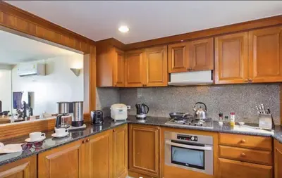 a large kitchen with wooden cabinets and appliances at Goodwill Beach House in Patong Beach