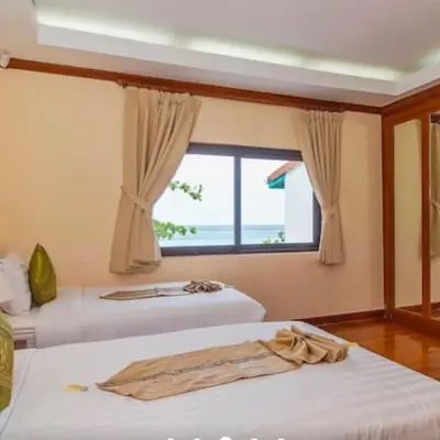 two beds in a room with a window at Goodwill Beach House in Patong Beach