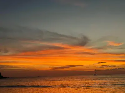 a sunset over the ocean with a boat in the water at The 4 Blocks at Kata noi in Kata Beach