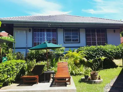 two chairs and an umbrella in front of a house at The Pavillon by The Pace Phuket Boutique Resort in Rawai Beach