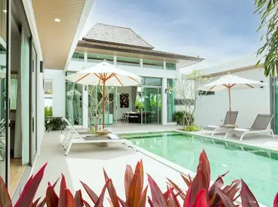 a house with a swimming pool with two umbrellas at Ananas villa Shambala grand Cherng Talay in Bang Tao Beach