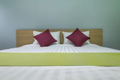 a bed with two purple pillows on it at Tha-ruea Residence in Thalang