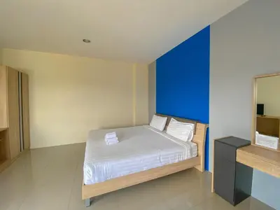 a bedroom with a bed with a blue wall at Tha-ruea Residence in Thalang