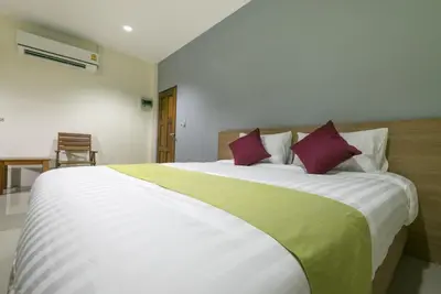 a bedroom with a large white bed with purple pillows at Tha-ruea Residence in Thalang