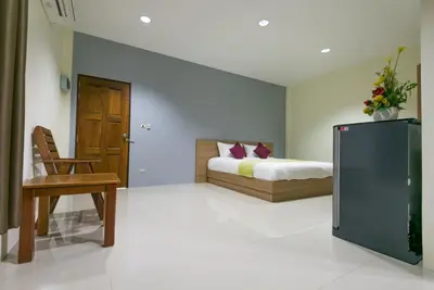 a bedroom with a bed and a chair and a tv at Tha-ruea Residence in Thalang