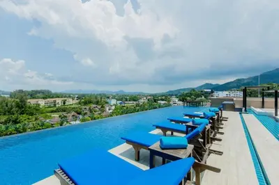 a row of blue lounge chairs on a swimming pool at Aristo 1 Phuket by RESAVA in Phuket Town