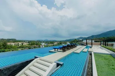 a swimming pool with tables and chairs on top of a building at Aristo 1 Phuket by RESAVA in Phuket Town