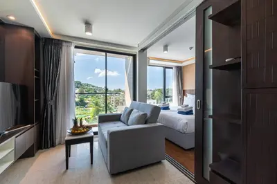 a bedroom with a couch and a bed and a window at Aristo 1 Phuket by RESAVA in Phuket Town