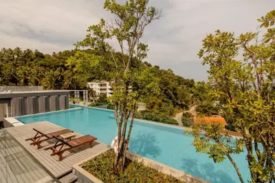 a swimming pool with a table and chairs next to trees at The Aristo 2 Condo Surin Beach in Surin Beach