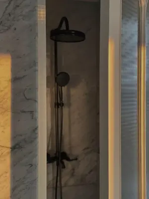 a showeroser with a hat on a pole in a bathroom at Hotel Verdigris in Phuket Town