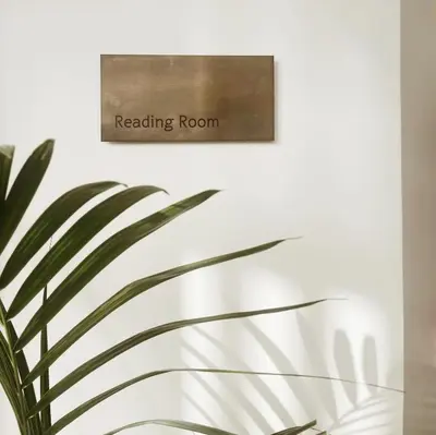 a reading room sign on a wall next to a plant at Hotel Verdigris in Phuket Town