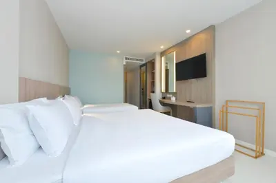 a bedroom with a large white bed and a desk at Grace Patong Hotel in Patong Beach