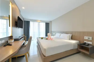 a hotel room with a large bed and a desk at Grace Patong Hotel in Patong Beach