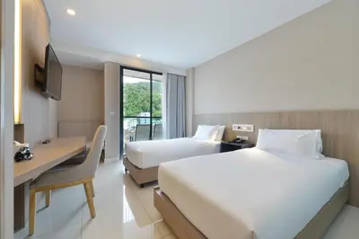a hotel room with two beds and a desk at Grace Patong Hotel in Patong Beach