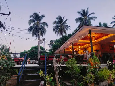 a building with a restaurant with palm trees in the background at The mantra resort in Ko Yao Yai