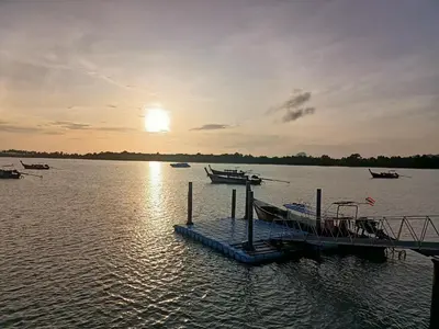 a dock with boats in the water at sunset at The mantra resort in Ko Yao Yai