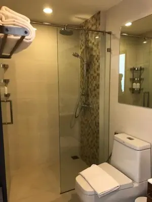 a bathroom with a shower and a toilet with a glass door at The Title West Wing@Rawai By Siri in Rawai Beach