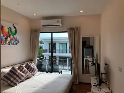 a bedroom with a bed with a view of a balcony at The Title West Wing@Rawai By Siri in Rawai Beach