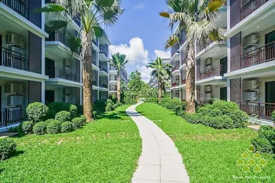 a path between two apartment buildings with palm trees at The Title West Wing@Rawai By Siri in Rawai Beach