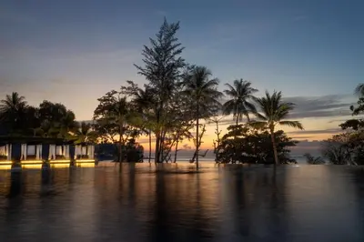 a flooded area with palm trees and a sunset at Hyatt Regency Phuket Resort in Kamala Beach