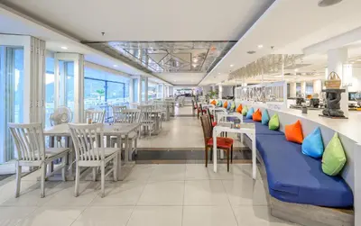 a restaurant with tables and chairs with colorful pillows at Andamantra Resort and Villa Phuket in Patong Beach