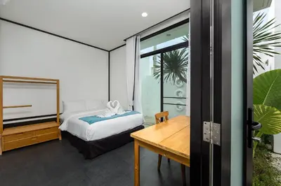 a bedroom with a bed and a wooden table at MONO LUX Villa x MonthStayZ Thailand in Chalong