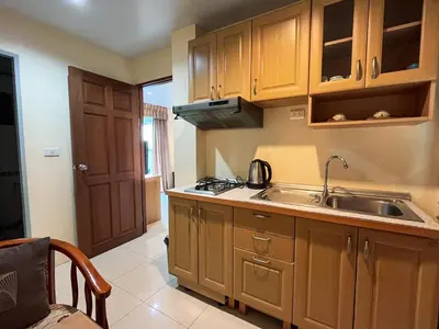 a kitchen with wooden cabinets and a sink at Purepamvillage in Kata Beach