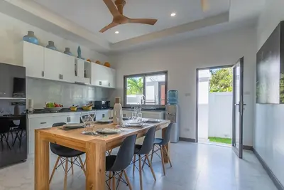 a kitchen with a wooden table and chairs at villa Akala in Ban Saiyuan (1)