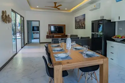 a dining room with a wooden table with chairs at villa Akala in Ban Saiyuan (1)