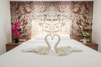 two white swans sitting on a bed in front of a wall at Tao Resort and Villas (SHA Extra+) in Phuket Town