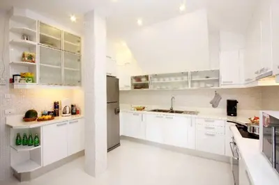a white kitchen with white cabinets and a refrigerator at Nakawanna Villa in Phuket Town