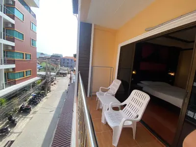 a balcony with two white chairs and a bed on it at Nanai 2 Residence Patong Phuket in Patong Beach