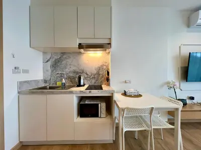 a kitchen with white cabinets and a table and a microwave at Aristo 2 Phuket by RESAVA in Surin Beach