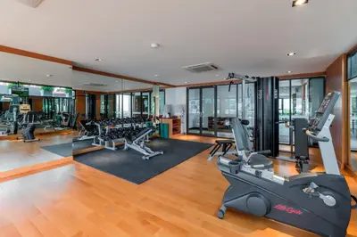 a gym with treadmills and exercise equipment in a building at The Charm Resort Phuket in Patong Beach