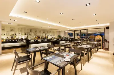 a restaurant with tables and chairs and a kitchen at The Charm Resort Phuket in Patong Beach