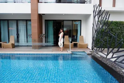a woman is standing next to a swimming pool at The Beach Heights Resort SHA Plus in Kata Beach