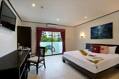 a bedroom with a bed and a desk and a window at Angus O'Tool's Guesthouse in Karon Beach
