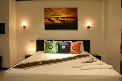 a bedroom with a large bed with colorful pillows at Angus O'Tool's Guesthouse in Karon Beach