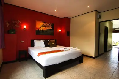 a bedroom with a large bed with red walls at Angus O'Tool's Guesthouse in Karon Beach