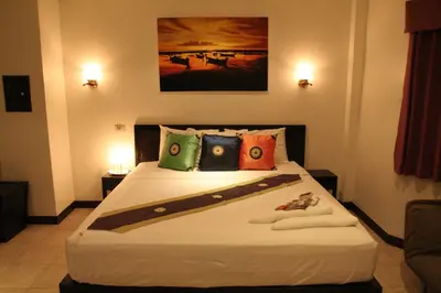 a bedroom with a large white bed with colorful pillows at Angus O'Tool's Guesthouse in Karon Beach