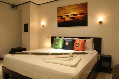 a bedroom with a large white bed with colorful pillows at Angus O'Tool's Guesthouse in Karon Beach