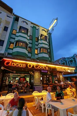 a group of people sitting at tables outside a restaurant at Angus O'Tool's Guesthouse in Karon Beach