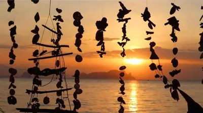 a group of hats hanging in front of a sunset at Koh Yao Noi Beach Resort in Ko Yao Noi