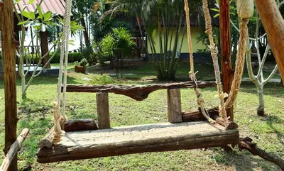 a log swing in a yard with a house at Koh Yao Noi Beach Resort in Ko Yao Noi