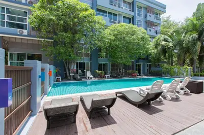 a swimming pool with lounge chairs next to a building at Kris - Modern Spacious 2 Bedrooms Condo with Pool in Patong Beach