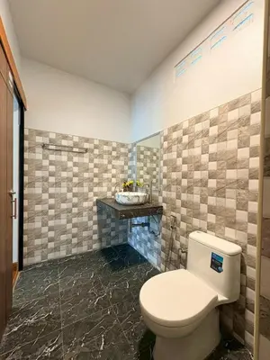 a bathroom with a toilet and a tiled wall at Baan I Ta Lay Koh Yao Noi in Ko Yao Noi