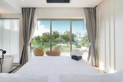 a bedroom with a bed and a large window at Capucine Villas in Kamala Beach