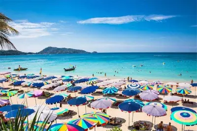 a beach with many umbrellas and people in the water at The Deck patong Luxury Apartments The Deck patong in Patong Beach