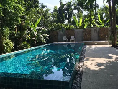 a swimming pool with blue tile in a backyard at Fern House Retreat in Chalong