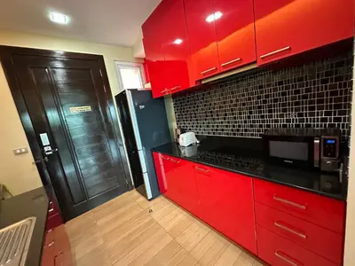 a red kitchen with red cabinets and a black refrigerator at Phuket Condominium Karon beach in Karon Beach
